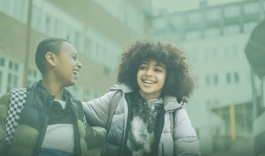Two adolescents arm in arm walking outside